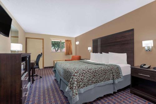 a hotel room with a bed and a flat screen tv at Days Inn by Wyndham Maumee/Toledo in Maumee