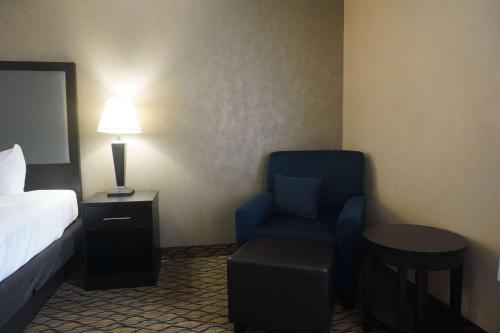 a room with a bed and a chair and a lamp at Baymont by Wyndham Bridgeport/Frankenmuth in Bridgeport