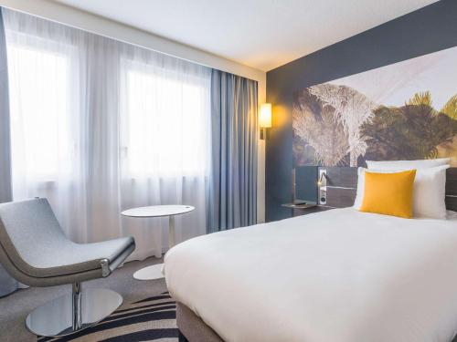 una habitación de hotel con una cama grande y una silla en Novotel Strasbourg Centre Halles, en Estrasburgo