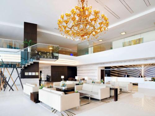 een lobby met witte meubels en een kroonluchter bij Novotel Dubai Al Barsha in Dubai