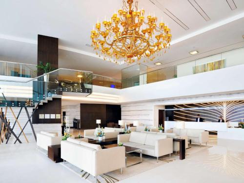 a lobby with white furniture and a chandelier at Novotel Dubai Al Barsha in Dubai