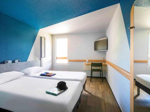 a hotel room with two beds and a tv at ibis budget Grenoble Voreppe in Voreppe
