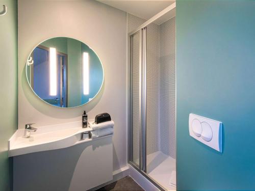La salle de bains est pourvue d'un lavabo et d'un miroir. dans l'établissement ibis budget Grenoble Voreppe, à Voreppe
