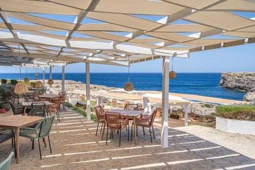 a patio with tables and chairs and the ocean at VORAMAR by 3VILLAS in Cala en Forcat