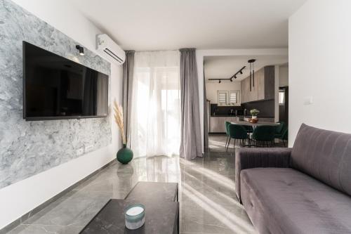 uma sala de estar com um sofá e uma televisão na parede em Luxury D Apartments em Bibinje