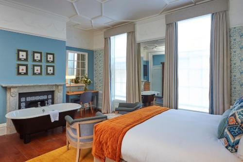 a bedroom with a bed and a desk and a fireplace at Hotel du Vin Winchester in Winchester