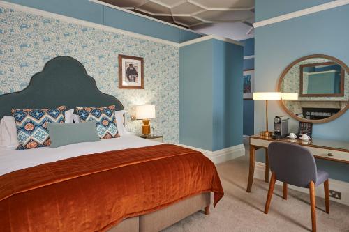 a bedroom with a bed and a desk and a mirror at Hotel du Vin Winchester in Winchester