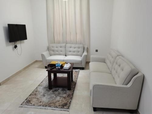 Roza Hotel Apartments في مسقط: غرفة معيشة مع كنبتين وطاولة قهوة