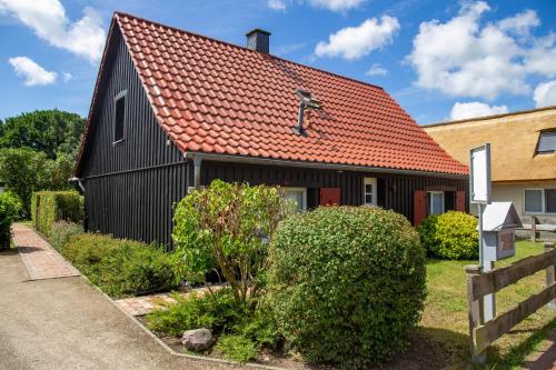 a black house with an orange roof at Sonnenwieck 01 in Wieck