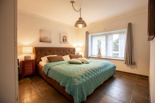 a bedroom with a bed with a green comforter and a window at Sonnenwieck 01 in Wieck