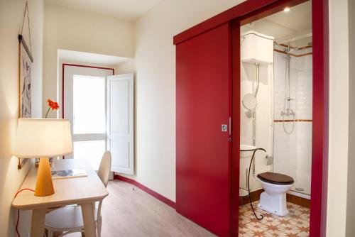 a red door in a bathroom with a toilet at Casa Lidador - Obidos in Óbidos