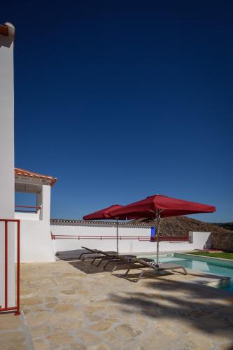 a red umbrella sitting next to a swimming pool at Casa Lidador - Obidos in Óbidos