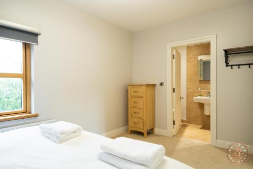 a white bedroom with a bed and a sink at Escape Ordinary at Castle Hume in Enniskillen