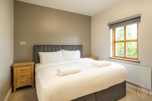 a bedroom with a large white bed and a window at Escape Ordinary at Castle Hume in Enniskillen