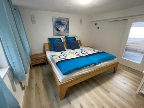 a bedroom with a bed with blue sheets and a window at Ferienwohnung an der Dill in Dillenburg