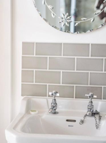 a bathroom sink with two faucets and a mirror at Room at the Inn in Lyme Regis
