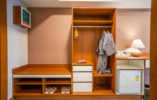a room with a closet with shelves and a desk at Siri Nakornpink Chiang Mai Hotel SHA Plus in Chiang Mai