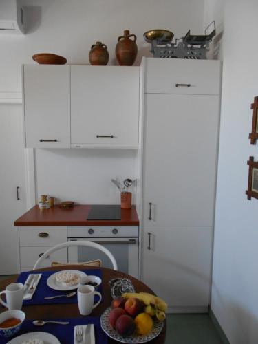 a kitchen with white cabinets and a table with fruit at Kalliope sea view summer house in Tripití