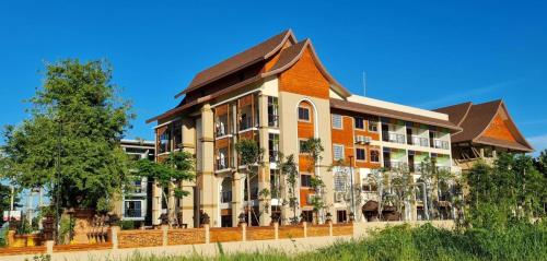 an orange and white building with trees in front of it at Siri Nakornpink Chiang Mai Hotel SHA Plus in Chiang Mai