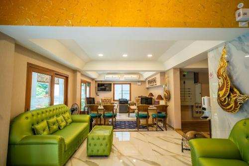 a living room with a green couch and chairs at Siri Nakornpink Chiang Mai Hotel SHA Plus in Chiang Mai