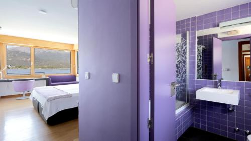 a purple bathroom with a bed and a sink at Posada del Agua in El Barraco