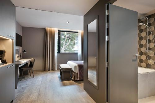 a hotel room with a bed and a desk and a bathroom at Upper Diagonal in Barcelona