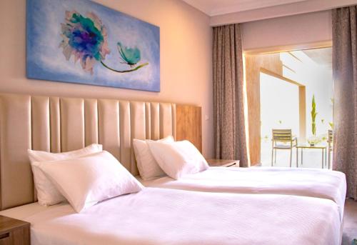 a hotel room with two beds with white sheets at Pickalbatros Jungle Aqua Park - Neverland Hurghada in Hurghada