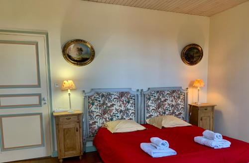 une chambre avec un lit rouge avec des serviettes dessus dans l'établissement Logis de La Touche, à Saint-Hilaire-des-Loges