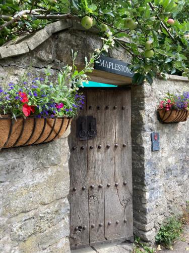 a door in a stone wall with flowers and plants at Maplestone in Shepton Mallet