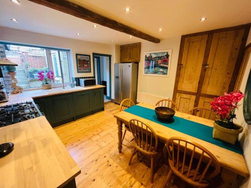 una cucina con tavolo e sedie in legno e bancone di Harbour Cottage a Folkestone