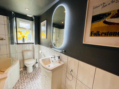 een badkamer met een wastafel, een toilet en een spiegel bij Harbour Cottage in Folkestone