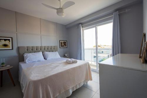 ein Schlafzimmer mit einem Bett und einem großen Fenster in der Unterkunft Ap. Alto padrão Costa Azul 200m da praia | ROTR304 in Rio das Ostras