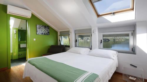 a bedroom with a large bed with green walls and windows at Posada del Agua in El Barraco