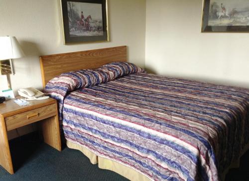 a hotel room with a bed and a desk with a phone at Travelodge by Wyndham Hudsonville in Hudsonville