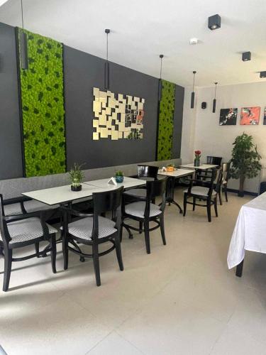 a dining room with tables and chairs and a green wall at Living Rooms in Skopje
