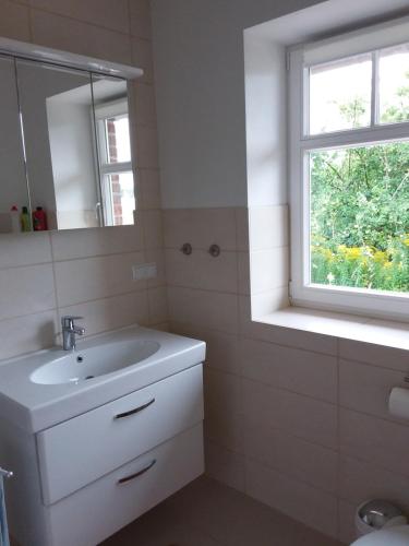 a bathroom with a sink and a mirror and a window at Haus Rosengarten- Ruhige Ferienwohnungen im Grünen in Sehlen