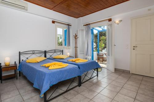 1 dormitorio con 1 cama con sábanas azules y almohadas amarillas en Apollon Rooms, en Pollonia