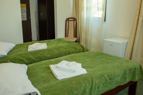 two beds in a room with green sheets and towels at Curtea Brancovenească in Constanţa