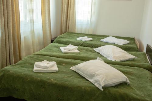 a bedroom with two beds with green sheets and white pillows at Curtea Brancovenească in Constanţa