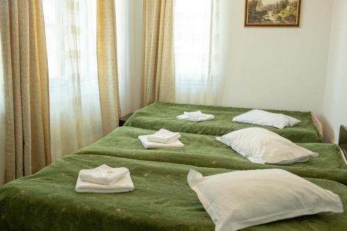 a bedroom with two beds with green sheets and white pillows at Curtea Brancovenească in Constanţa