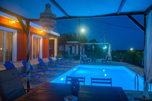 uma piscina à noite com cadeiras à volta em Estate ''Tsoukalas Group'' em Ambelókipoi