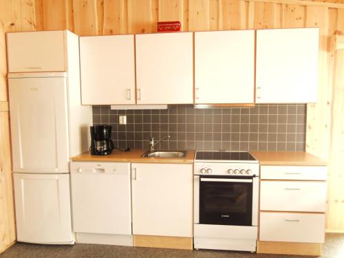 a kitchen with white cabinets and a stove and refrigerator at Lensmansgarden Fjøsen in Innfjorden