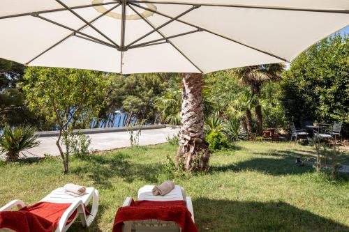 two beds under an umbrella in the grass at Sea View & Beach Luxury Palm Garden Split Apartment in Split