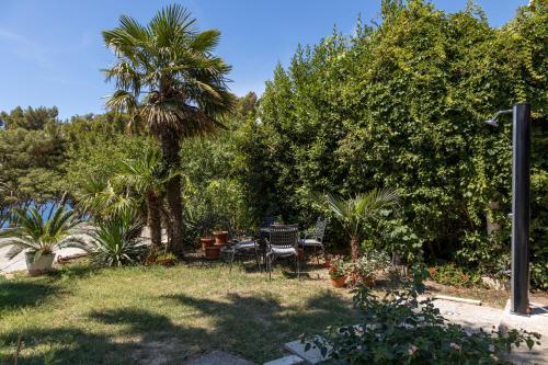a garden with a table and chairs and a palm tree at Sea View & Beach Luxury Palm Garden Split Apartment in Split