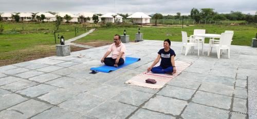 two people sitting on yoga mats on a patio at Jawai Bera Leopard Camp in Bera