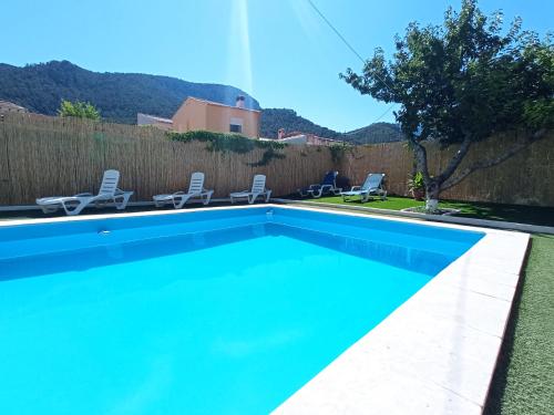 a swimming pool with chairs and a fence at Alojamiento Rural Puente Honda in Siles