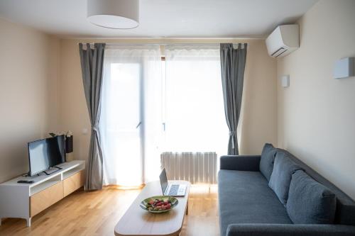 a living room with a blue couch and a tv at Modern and Spacious apartments in the City Centre in Sofia