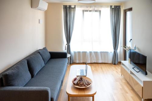 a living room with a blue couch and a table at Modern and Spacious apartments in the City Centre in Sofia