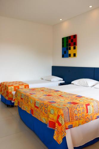 two beds in a room with a colorful blanket on them at Hotel Açoriano in Penha