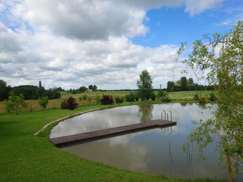 a pond with a wooden bridge in a field at MĖTA in Birštonas